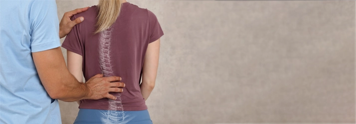 Chiropractic Lancaster PA Scoliosis A chiropractor performs a back examination, with an outline of a curved spine visible on the patient's back.